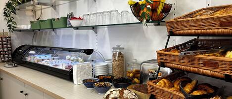 Un mostrador de panadería con diversos productos horneados, incluyendo pan y pasteles, y una vitrina con postres.