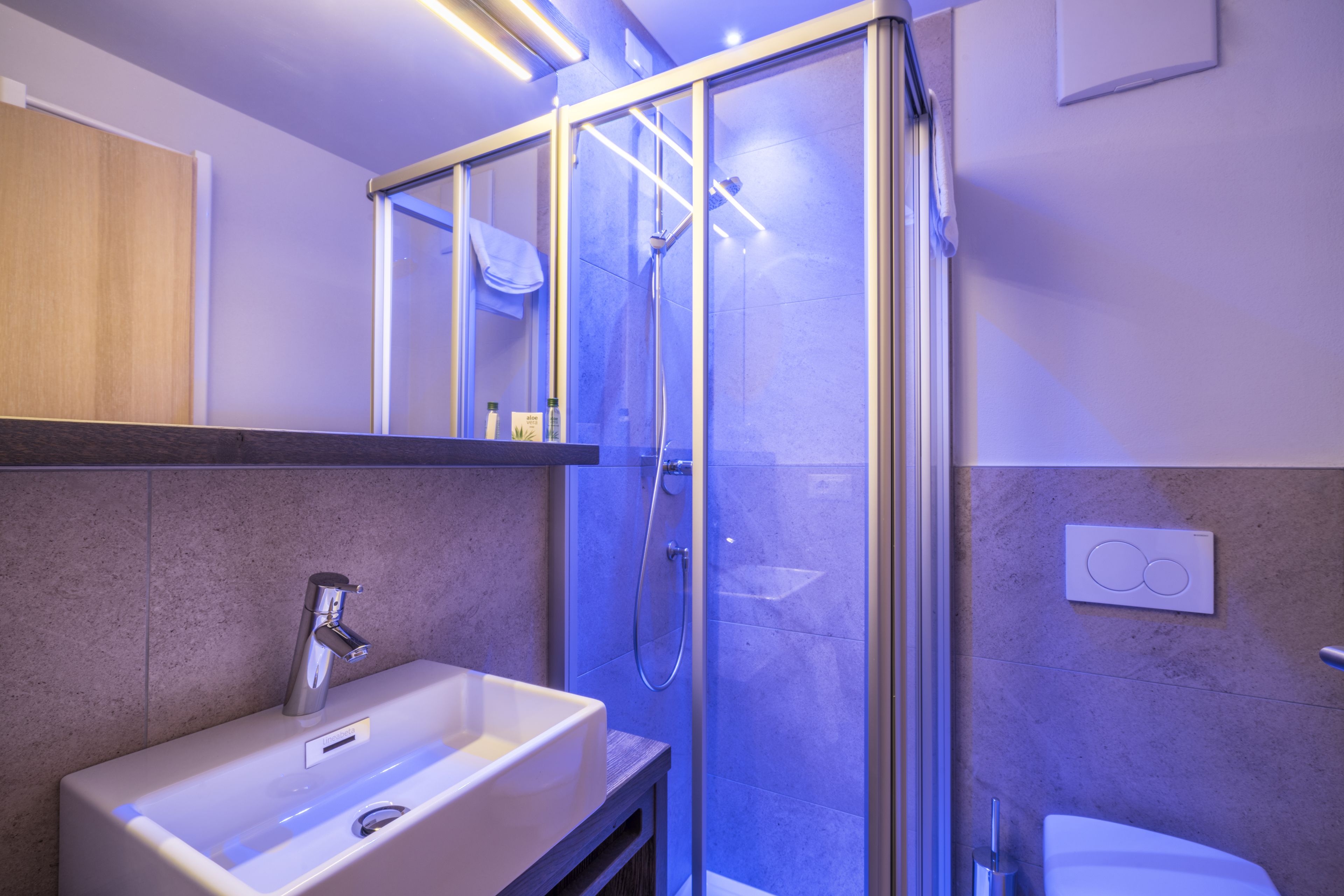 A modern bathroom with a glass-enclosed shower, a white sink, and a toilet.