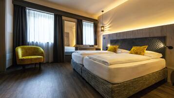 Una habitación de hotel con una cama grande, una silla y un ventanal con cortinas.