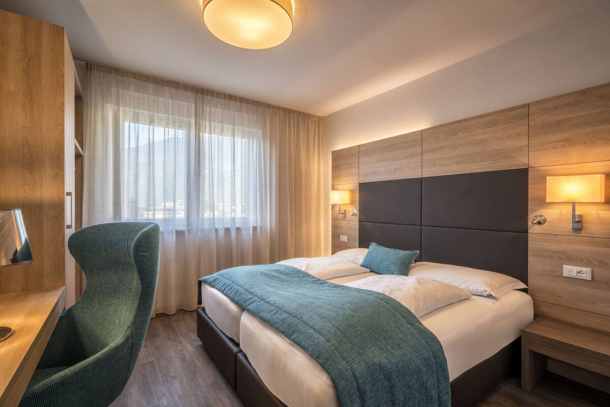 Una habitación de hotel moderna con una cama grande, un escritorio y una silla.