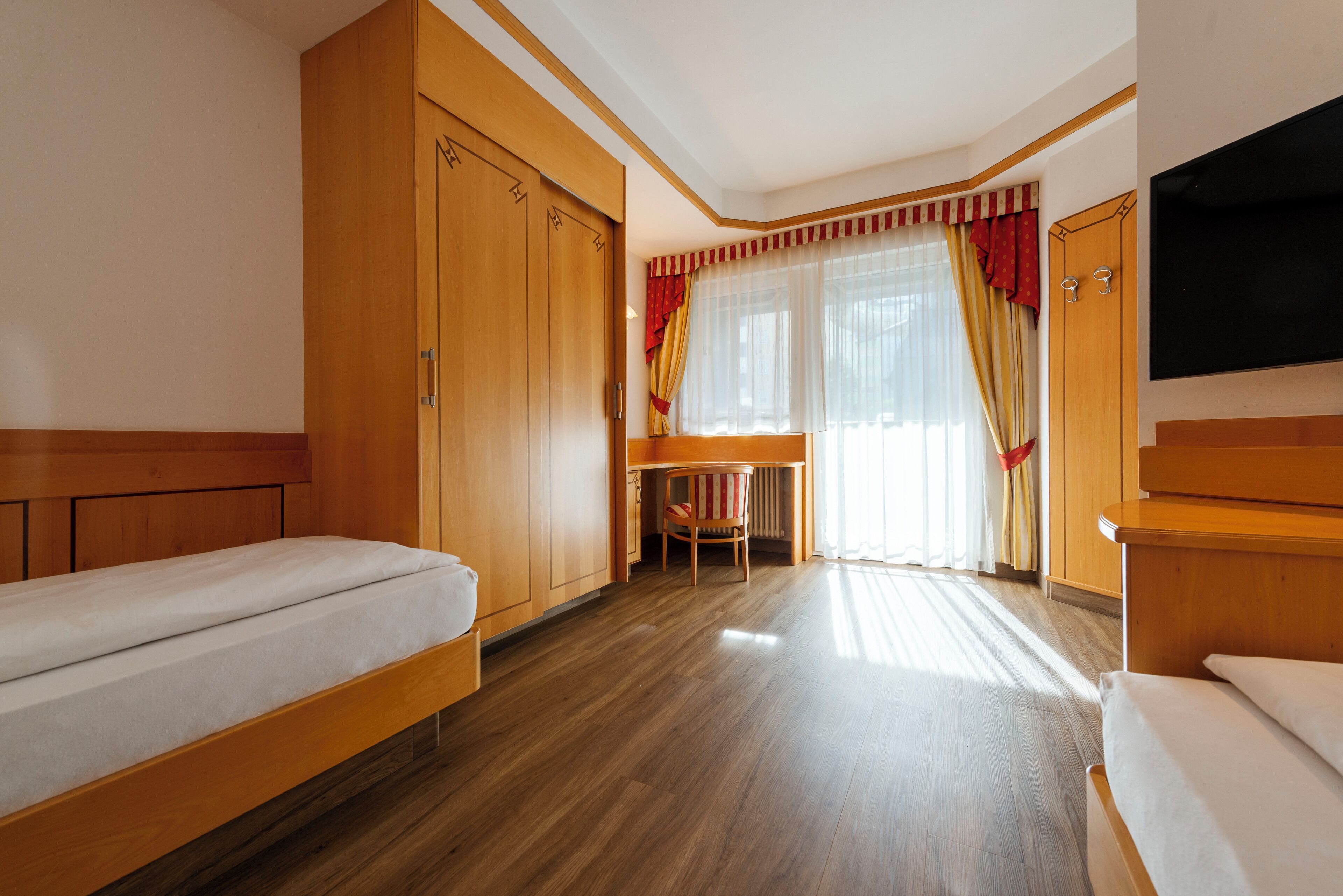 A hotel room with a bed, a desk, and a TV.