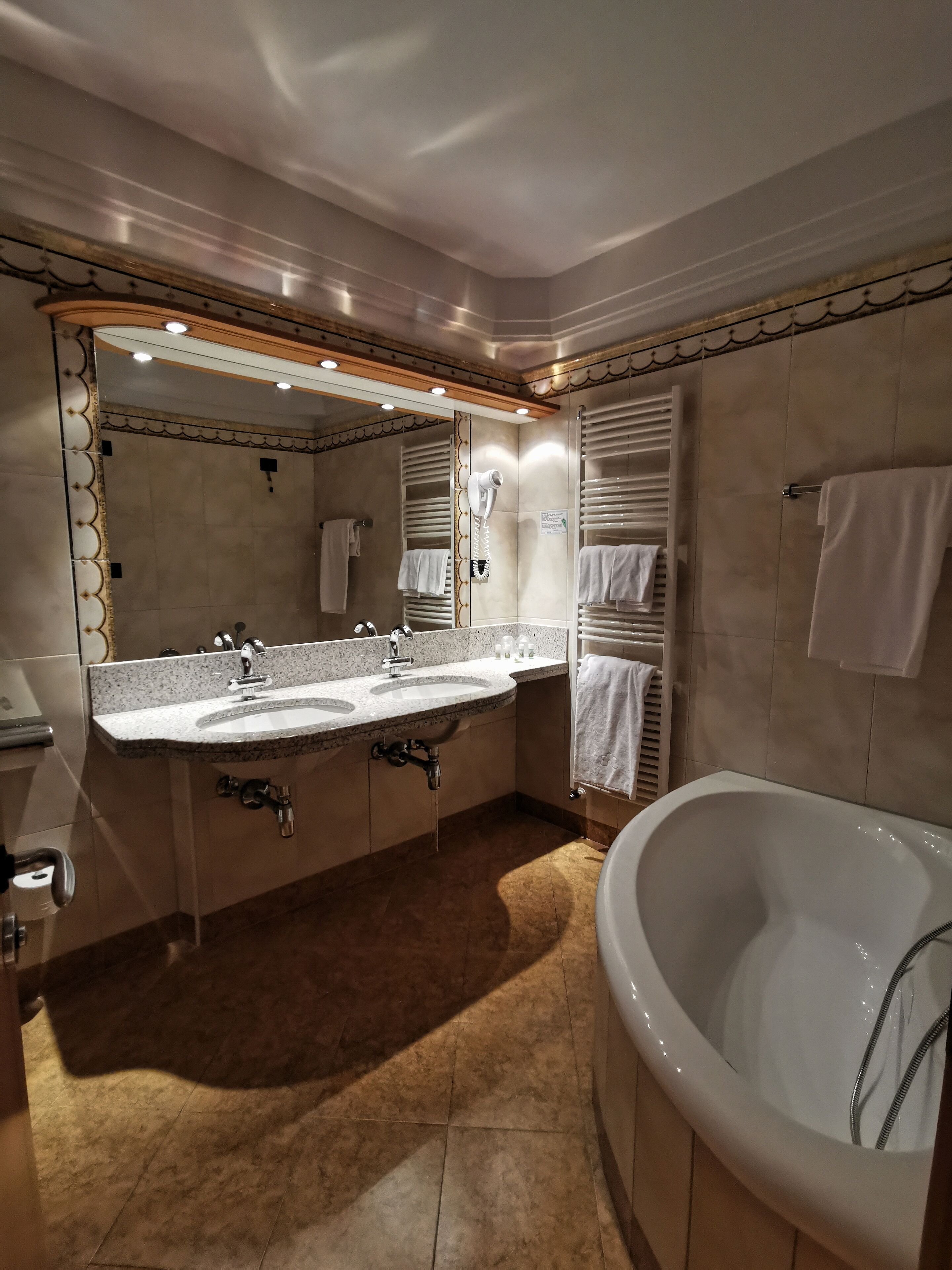 Un baño moderno con una bañera grande, dos lavamanos y un espejo de tocador.