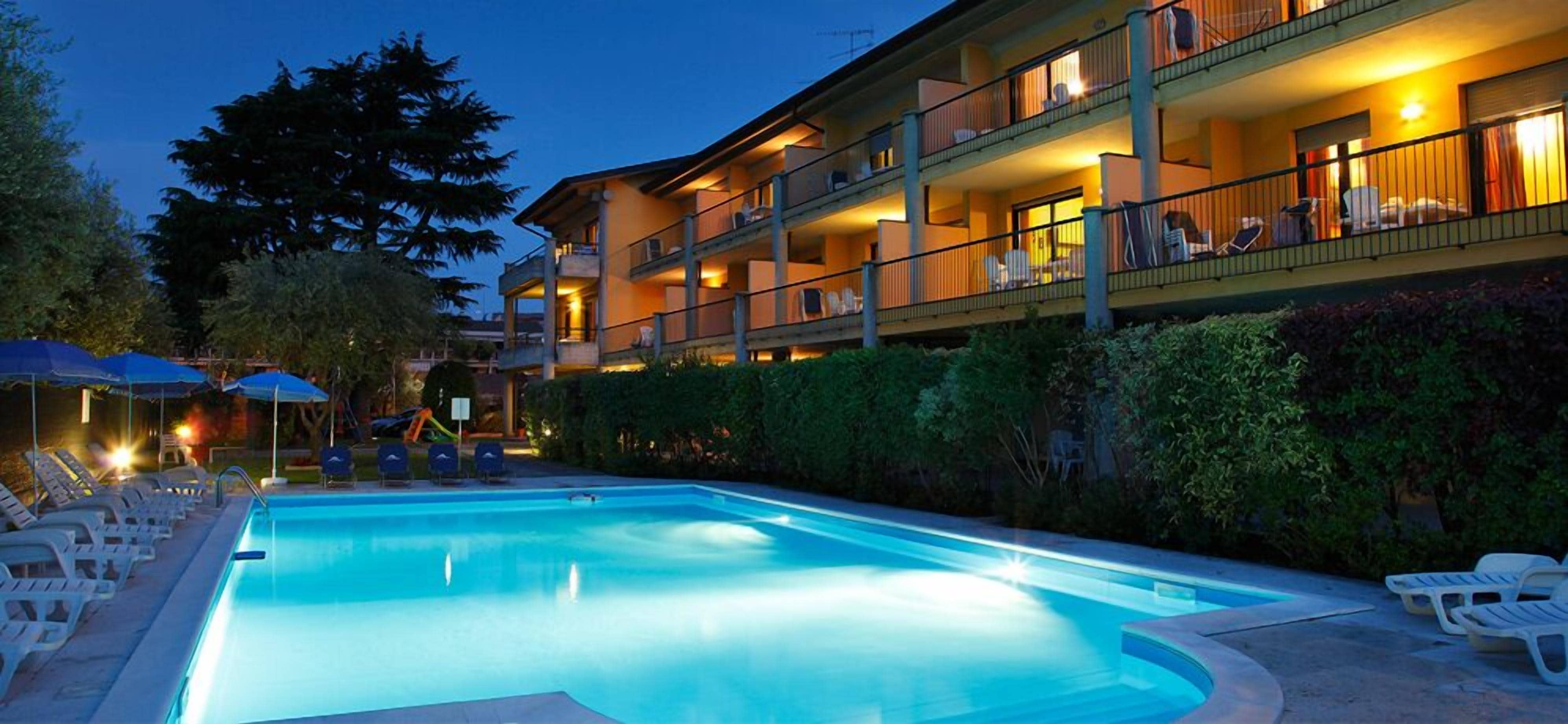 Et hotel med swimmingpool, flere balkoner og udendørs siddepladser.