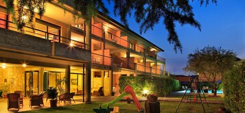 Un hotel de varios pisos con terraza exterior y zona de piscina.