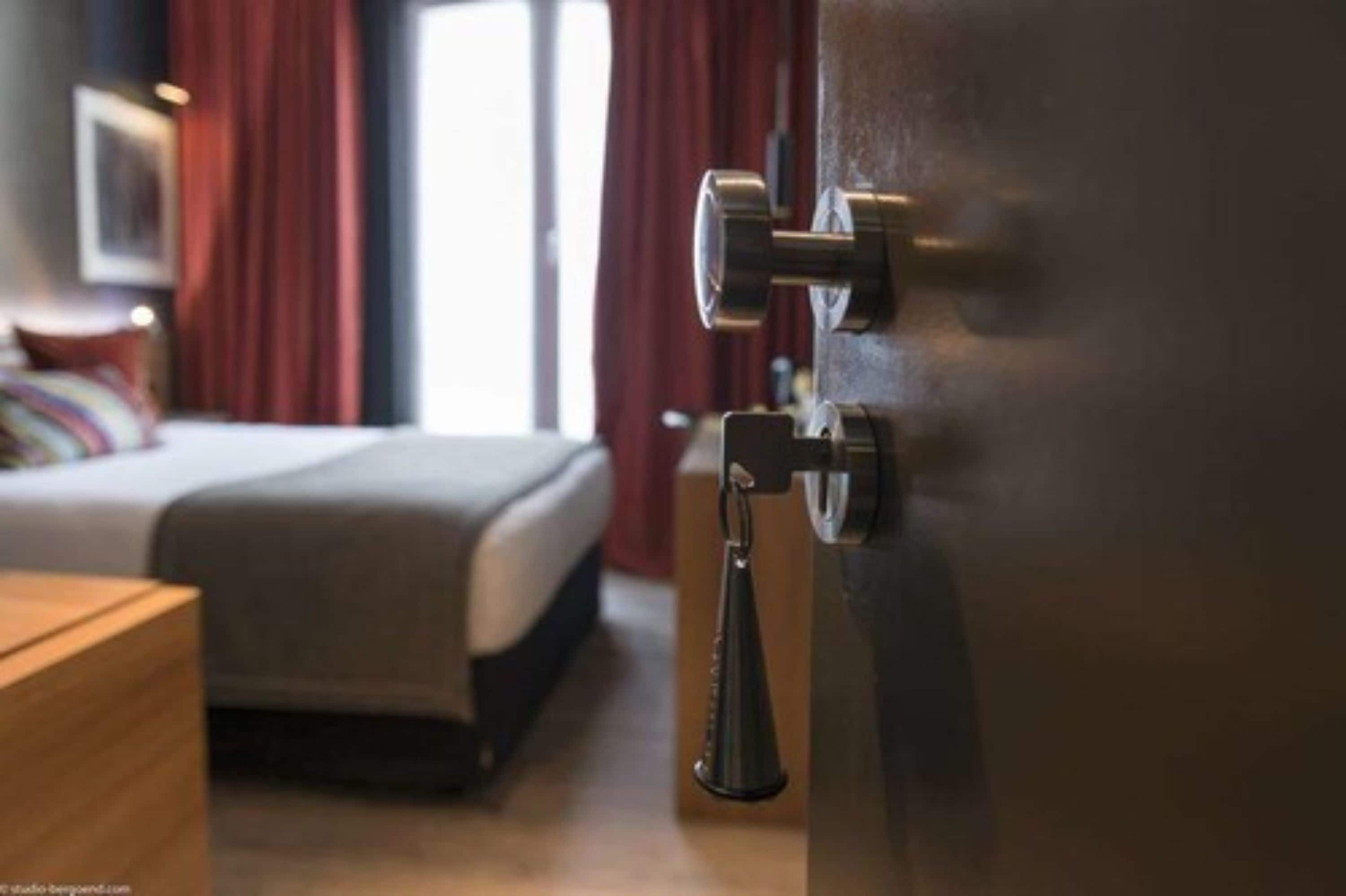 Ein Hotelzimmer mit einem Bett, einem Nachttisch aus Holz und einer Tür mit Griff.