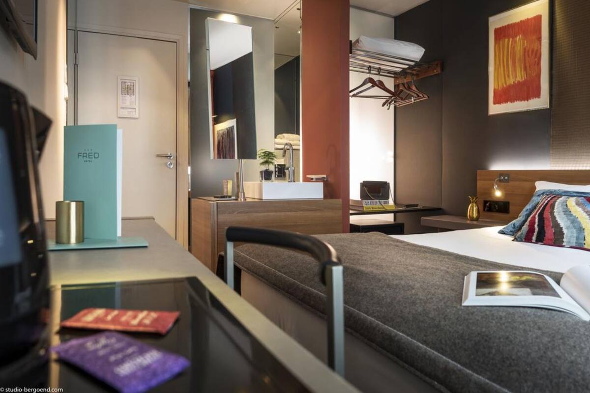 Una habitación de hotel moderna con cama, mesita de noche y escritorio con silla.
