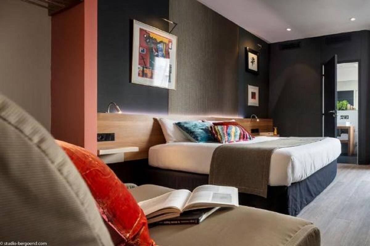 Una habitación de hotel moderna con una cama, un escritorio, una silla y un televisor.