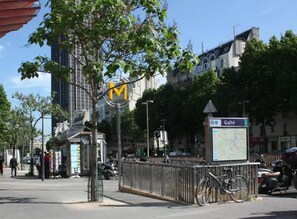 A city street with a bus stop, a bicycle, and a map sign. - Tipi Hôtel (Paris)