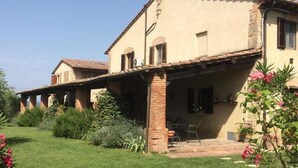Una casa de dos plantas con un porche cubierto y un jardín.