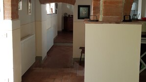 Un pasillo con arcos de ladrillo, paredes blancas y suelo de baldosas.