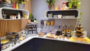A buffet setup with various food items, condiments, and decorative plants. - Hotel Virgina (Paris)