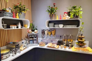 Una mesa de buffet con diversos alimentos, salsas y plantas decorativas.