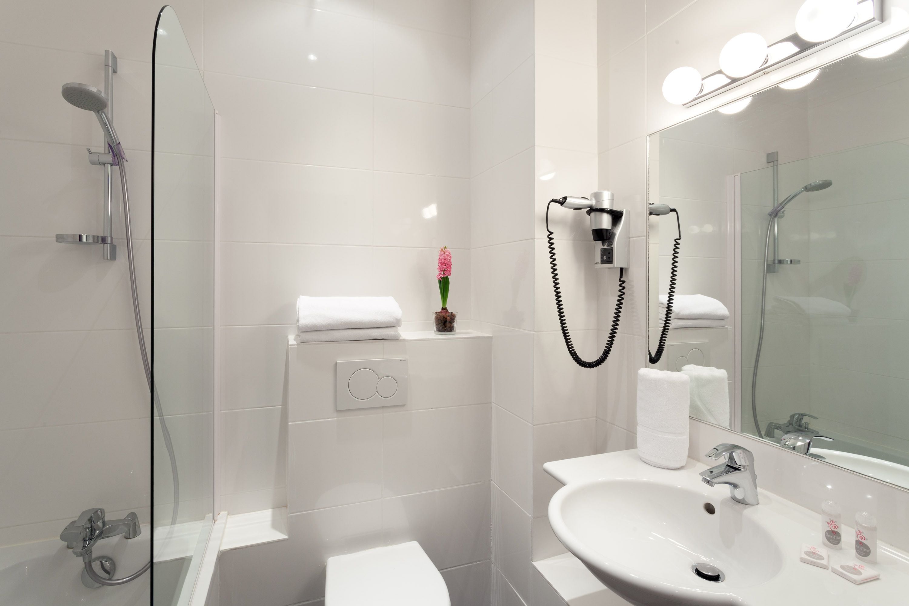 Une salle de bain moderne avec une douche à parois de verre, un lavabo blanc et un grand miroir avec éclairage intégré.