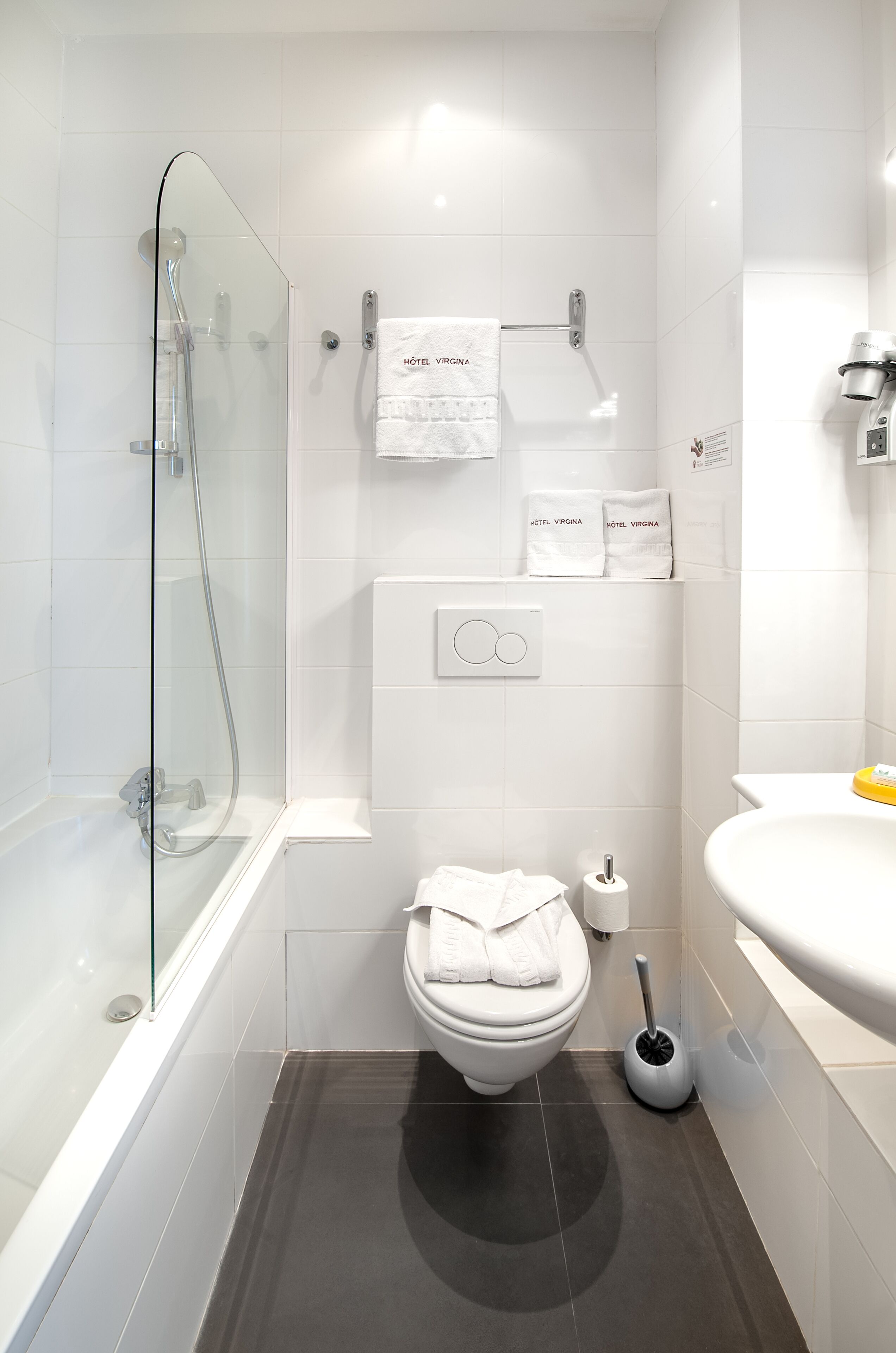 A modern bathroom with a glass-enclosed shower, a toilet, and a sink.