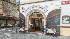 Un café-restaurant avec une terrasse, un bâtiment en pierre et des menus écrits à la craie.