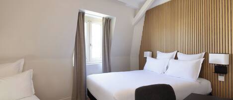 A hotel room with a large bed, a desk, and a window with curtains.