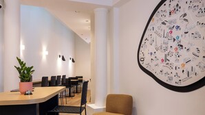 Un interior moderno con una mesa redonda de comedor, sillas negras, una alfombra colorida y una pared con un mural de paisaje urbano.