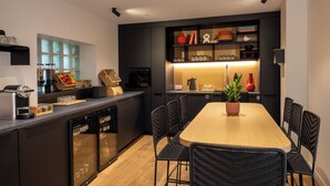 Una cocina moderna con una isla central, armarios negros y una mesa de comedor de madera con sillas.