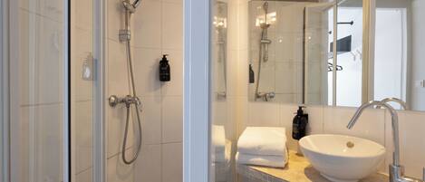A modern bathroom with a glass shower enclosure, a white sink, and a large mirror.