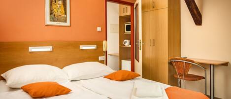 A hotel room with a bed, a chair, a desk, and a wardrobe.