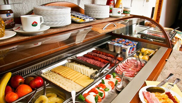 A buffet with various food items including fruits, cheeses, meats, and breakfast items. - Manzard Panzio (Budapest)