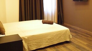 A hotel room with a large bed, a flat-screen TV mounted on the wall, and a wooden floor. - Budapest Royal Suites II (Budapest)