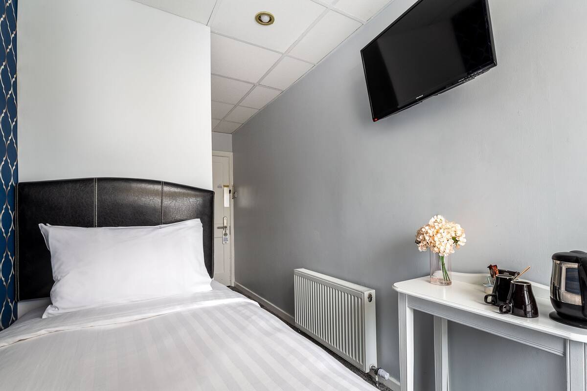 Ein Hotelzimmer mit Bett, Wandfernseher, Kaffeemaschine und Heizkörper.