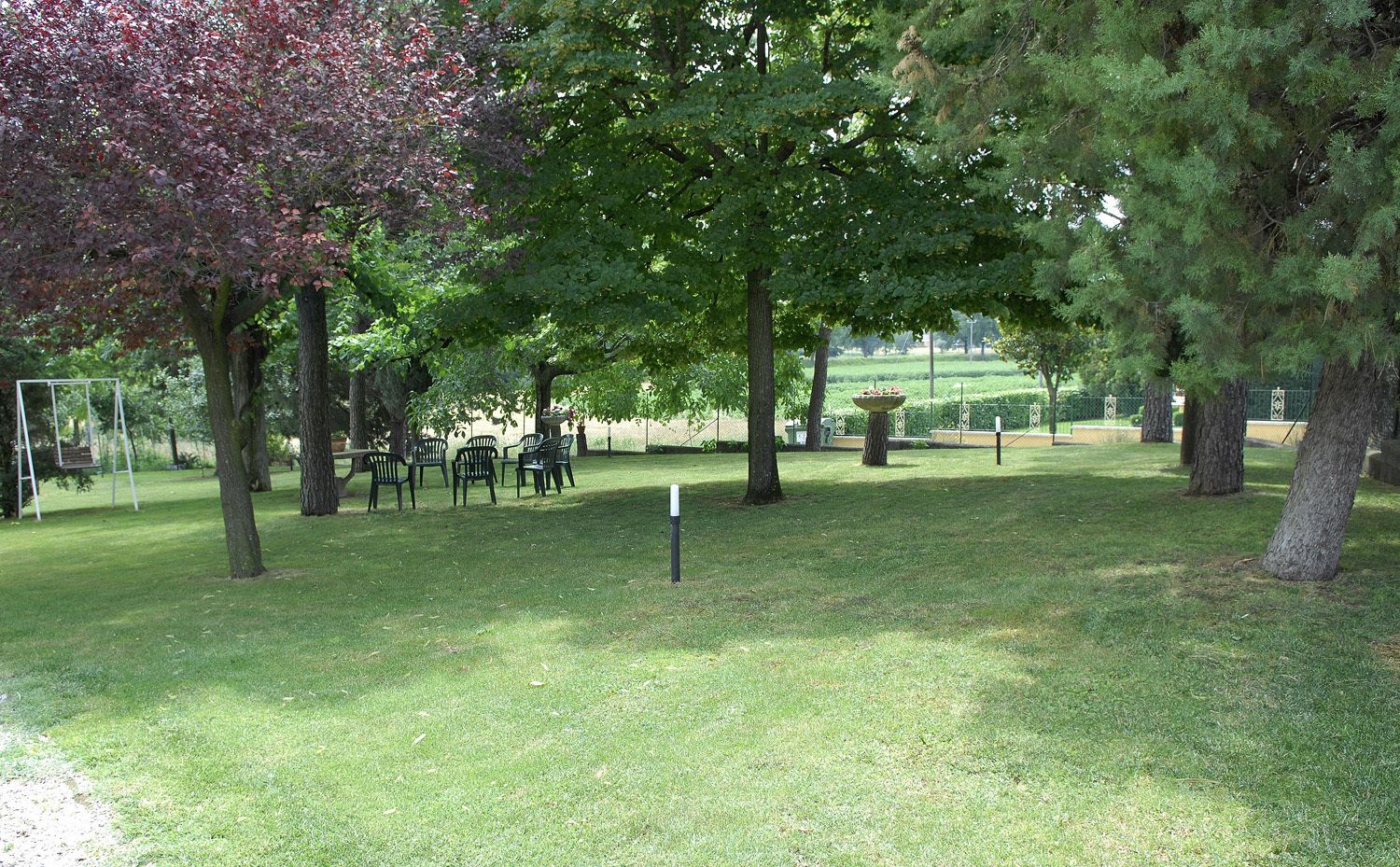A park with trees, a picnic table, and a swing set.