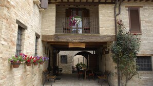 A building with a balcony, potted plants, and a sign above the entrance. - Agriturismo Il Borghetto (Montefalco)