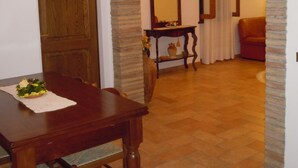 A dining area with a wooden table and chairs, an archway leading to another room, and a mirror on the wall. - Agriturismo Il Borghetto (Montefalco)