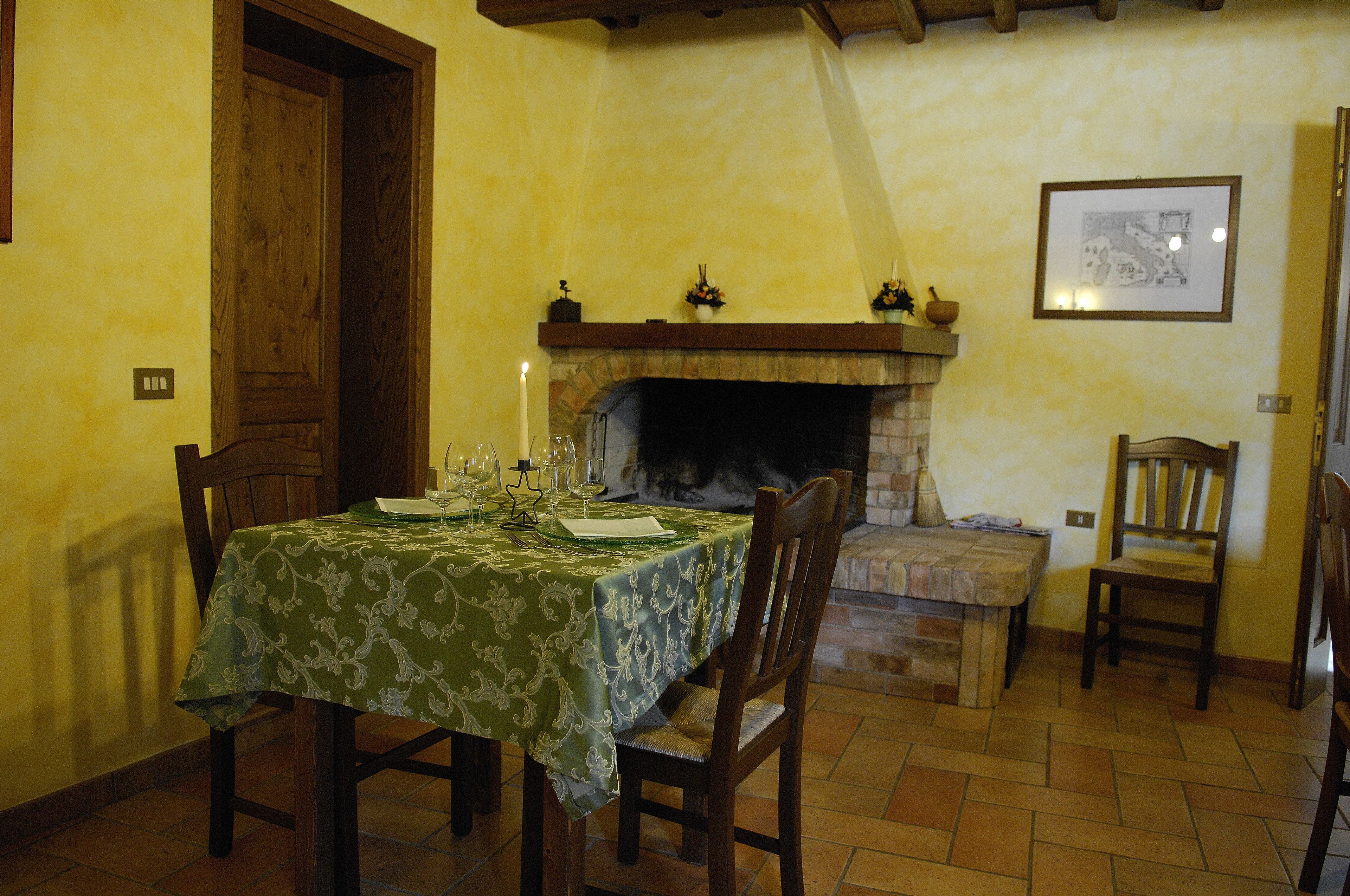 Un comedor con una mesa preparada para cuatro, una chimenea y un cuadro en la pared.