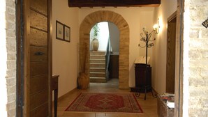 A hallway with a wooden door, a rug, a staircase, and a vase. - Agriturismo Il Borghetto (Montefalco)