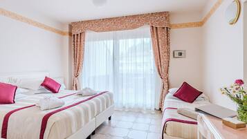 A hotel room with two beds, a desk, and a window with curtains.