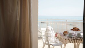 A balcony with a table set for breakfast, a white chair, and a view of the sea. - Residence San Paolo (Ravenna)