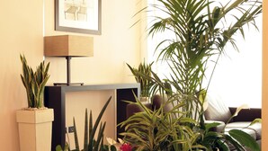 A living room with a sofa, a coffee table, and several potted plants. - Residence San Paolo (Ravenna)