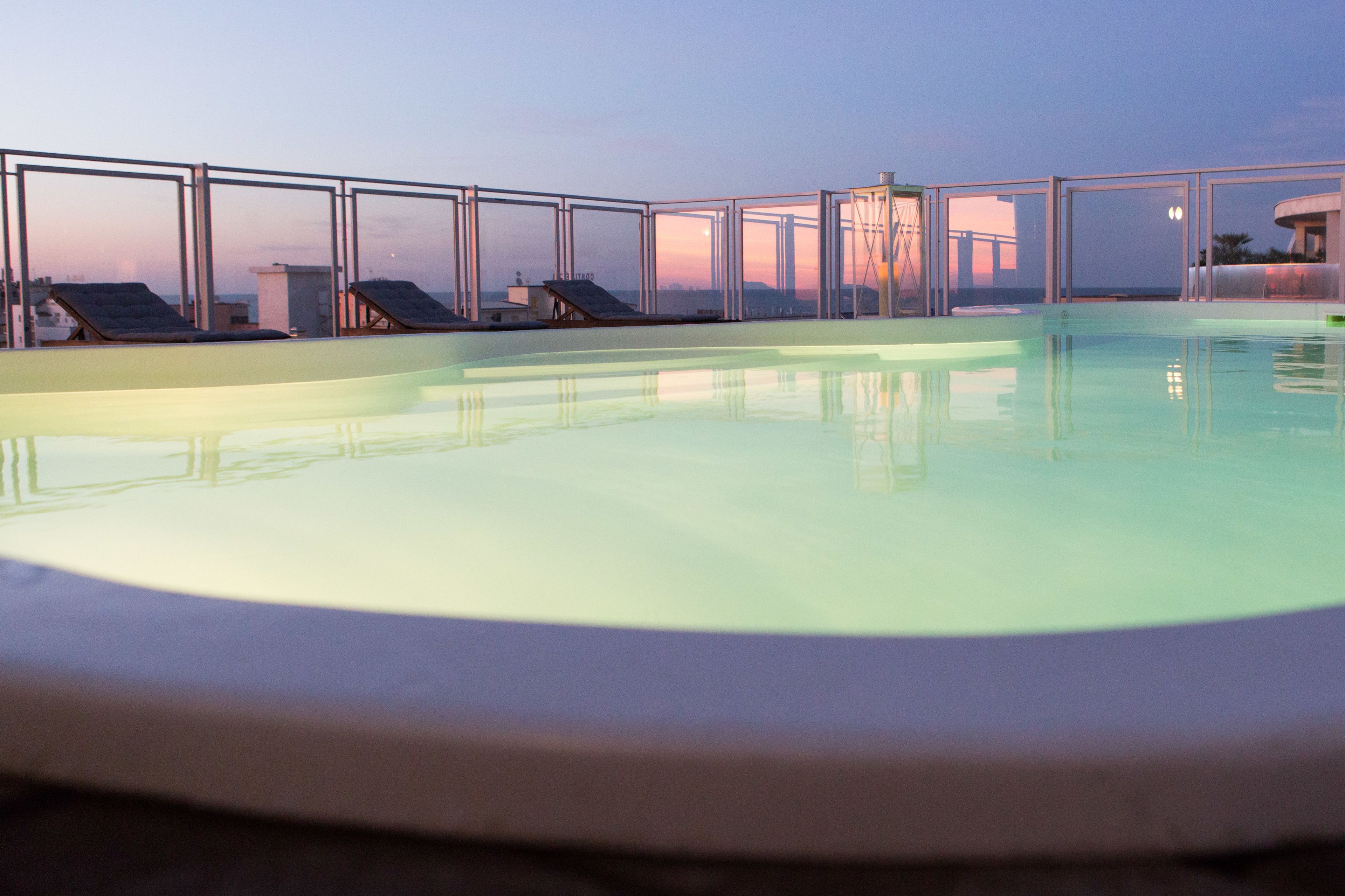 Une piscine sur le toit, dotée de rampes en verre transparent et de chaises longues.