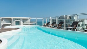 A rooftop infinity pool with lounge chairs and a glass railing overlooking the ocean. - Perla Verde Hotel (Cervia)