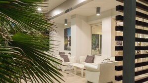 A modern interior with white sofas, a glass coffee table, and a large plant. - Perla Verde Hotel (Cervia)