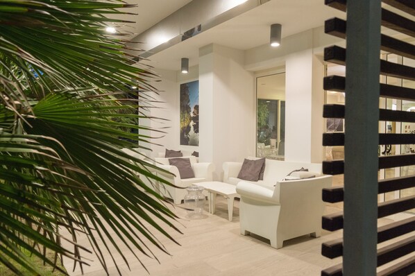 Un interior moderno con sofás blancos, una mesa de centro de vidrio y una planta grande.