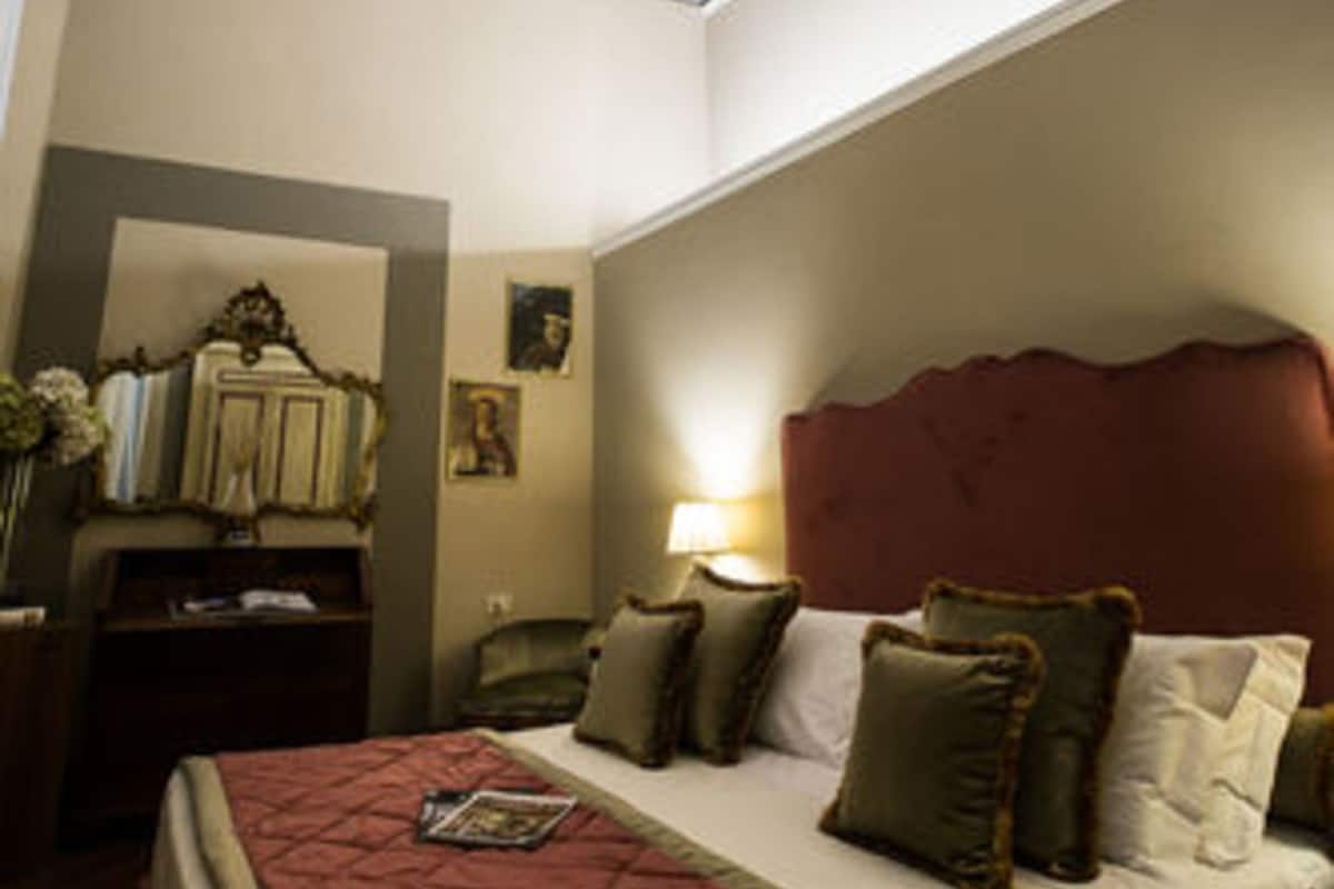A bedroom with a bed, a nightstand, a lamp, a mirror, and a ceiling mural.