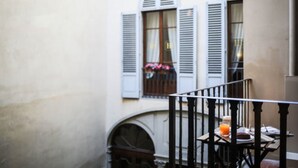A balcony with a table, a chair, and a window with shutters. - Hotel Burchianti (Florence)