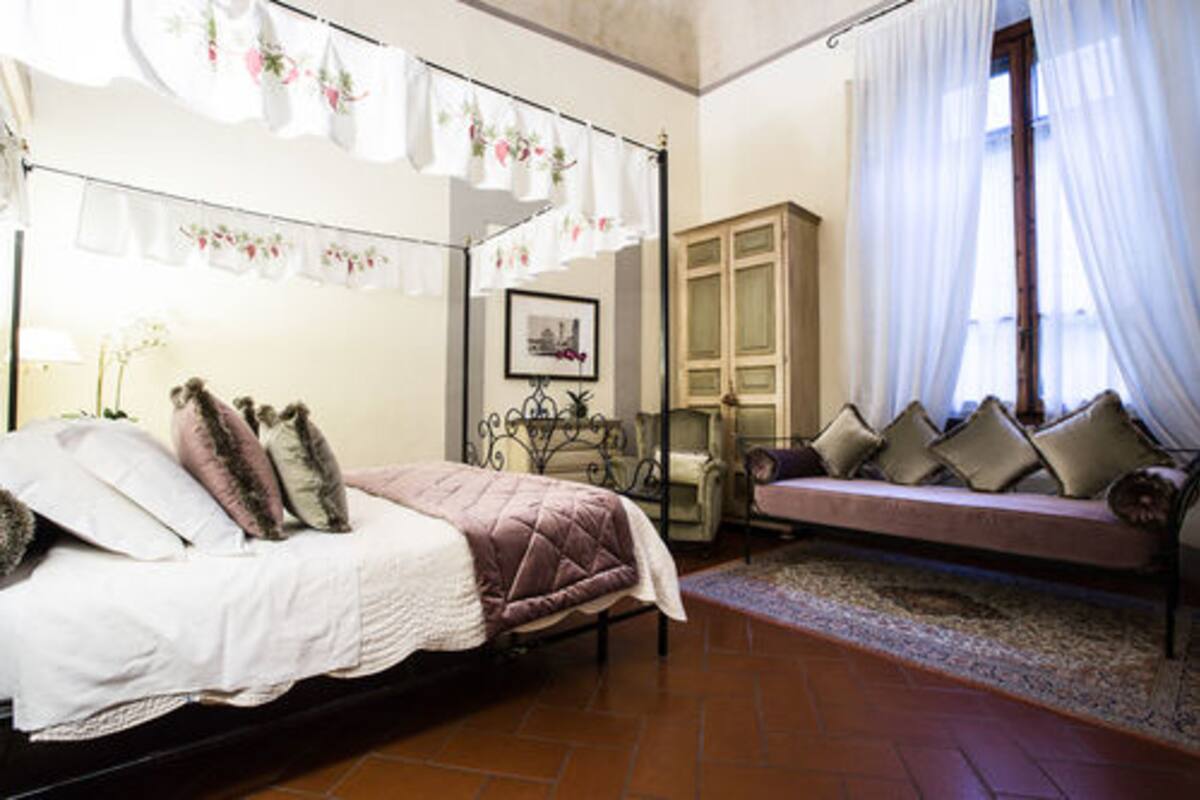 A bedroom with a bed, a sofa, a cabinet, and a window with curtains.