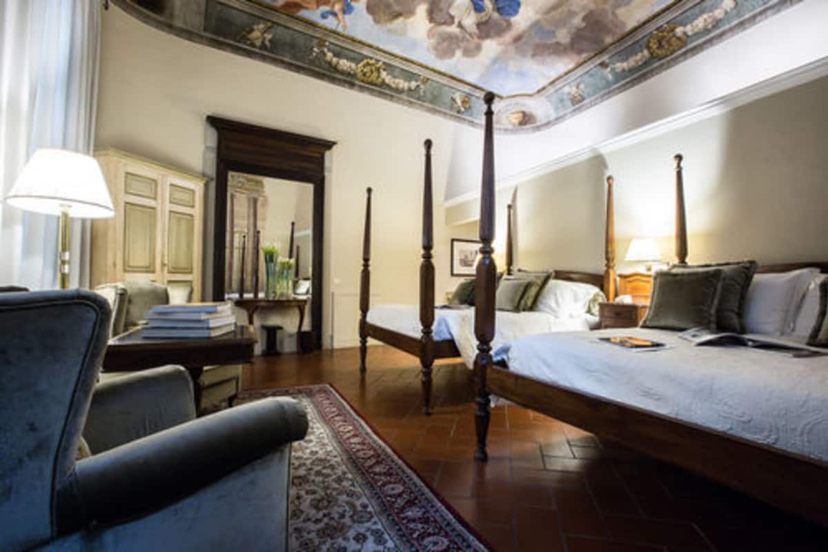 A four-poster bed with a wooden frame, a bedside table with a lamp, and a chair.