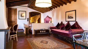 A cozy living room with a wooden ceiling, a large rug, a sofa with cushions, and a chair.
