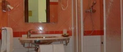 A bathroom with a sink, mirror, and shower.