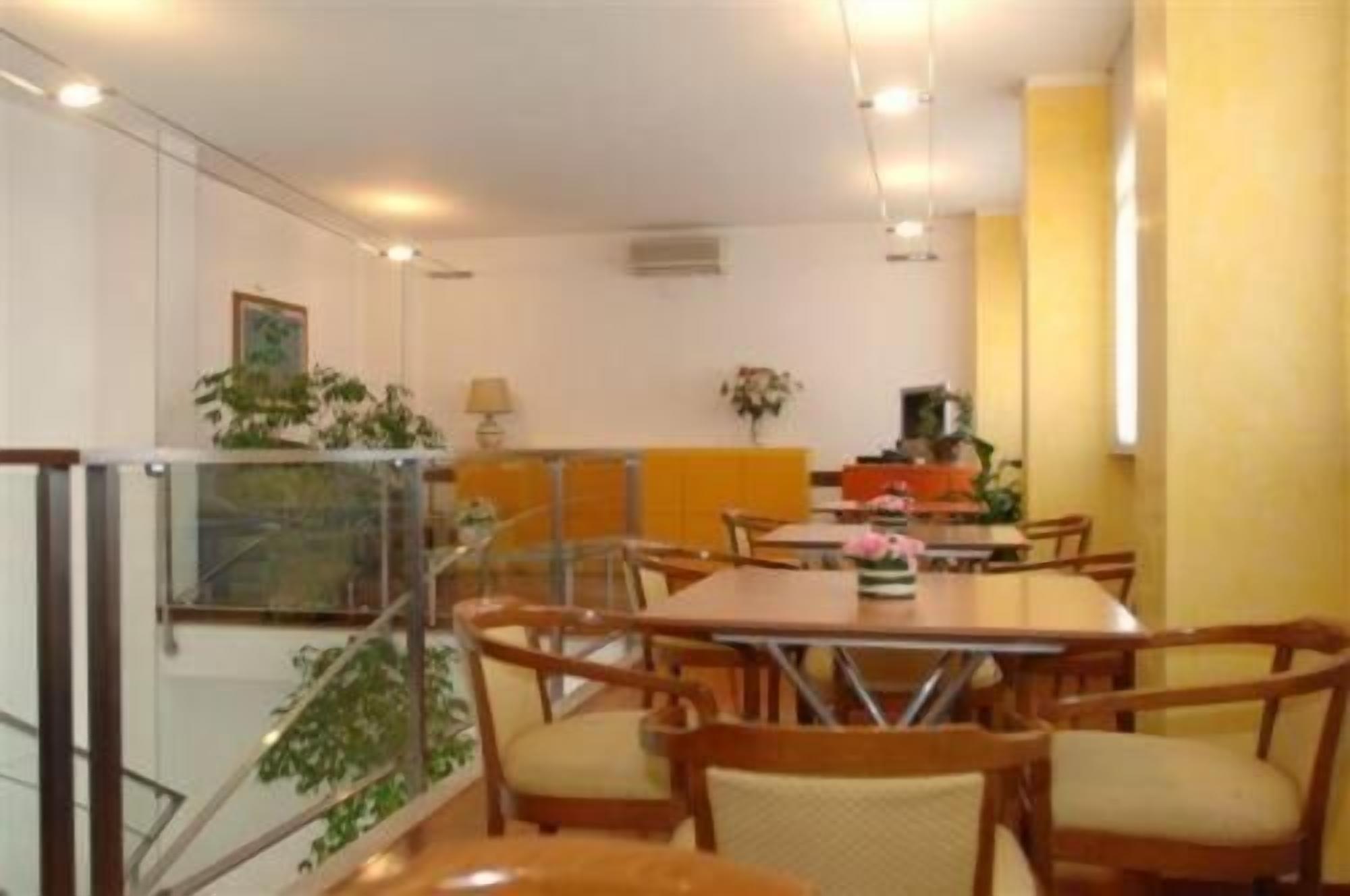 A dining area with wooden tables and chairs, a staircase, and a plant.