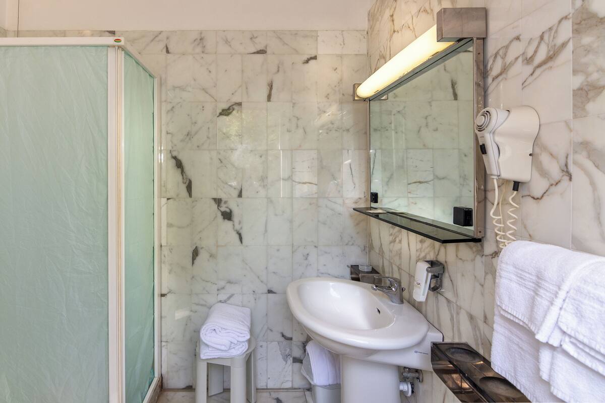 A bathroom with a shower, sink, and mirror.