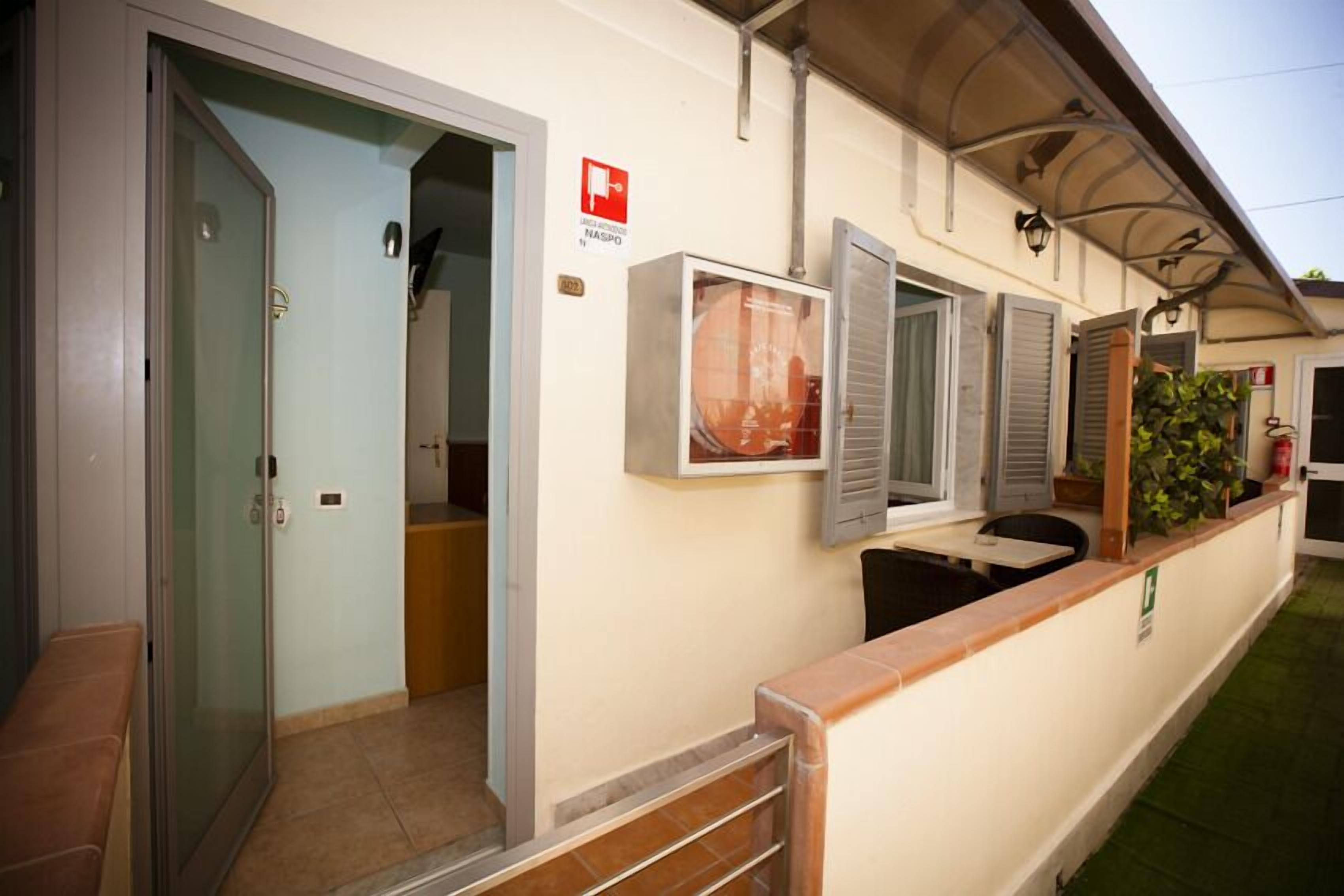A hotel entrance with a glass door, a reception desk, and a sign indicating a smoking area.