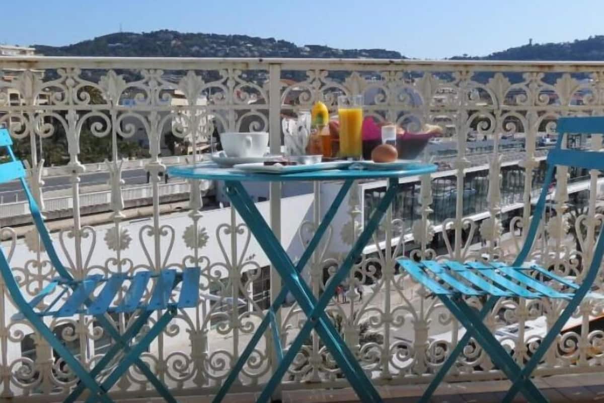 A balcony with a table set for a meal, a chair, and a decorative fence.