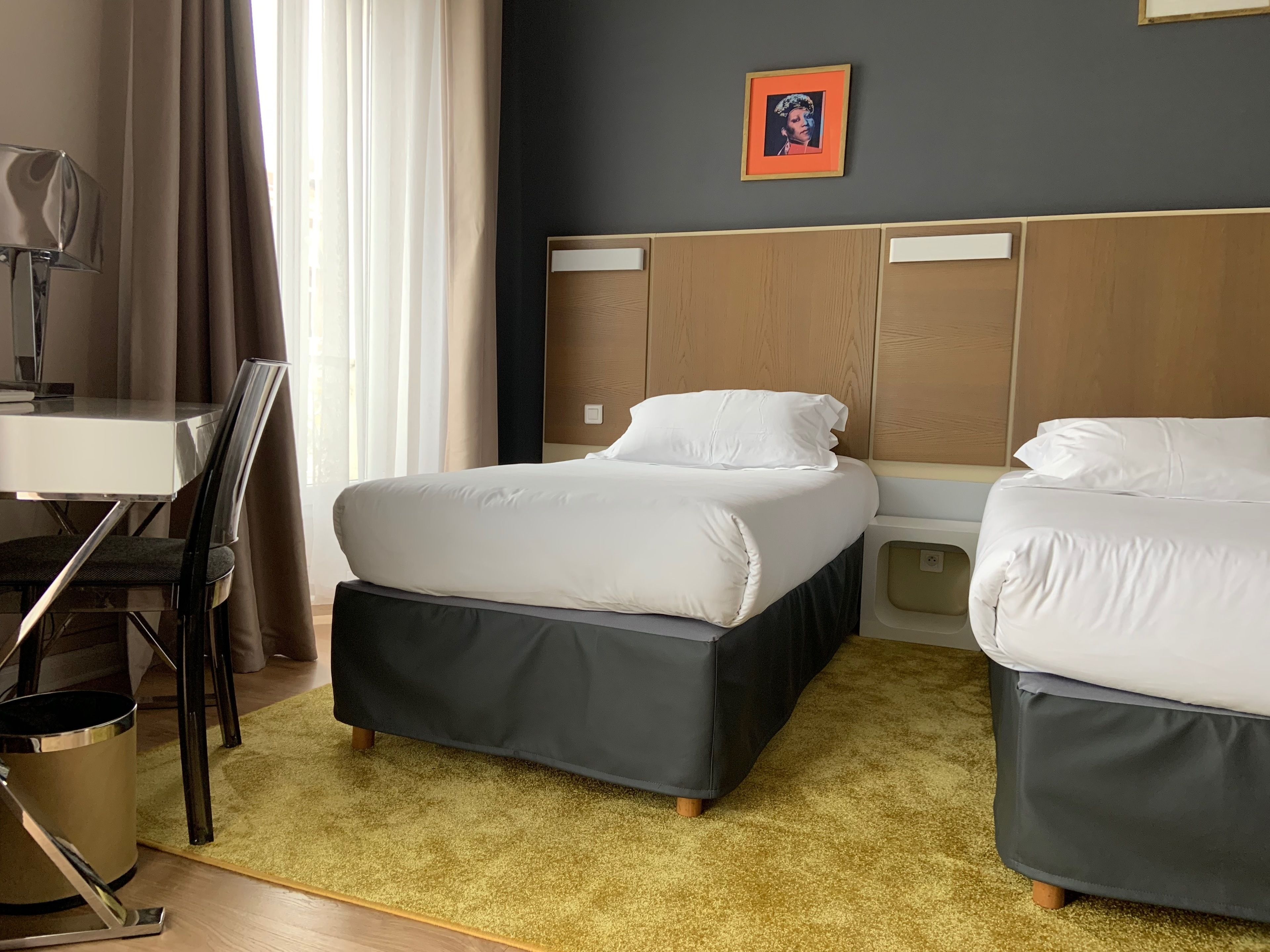 Een hotelkamer met een bed, nachtkastjes, een bureau en een stoel.